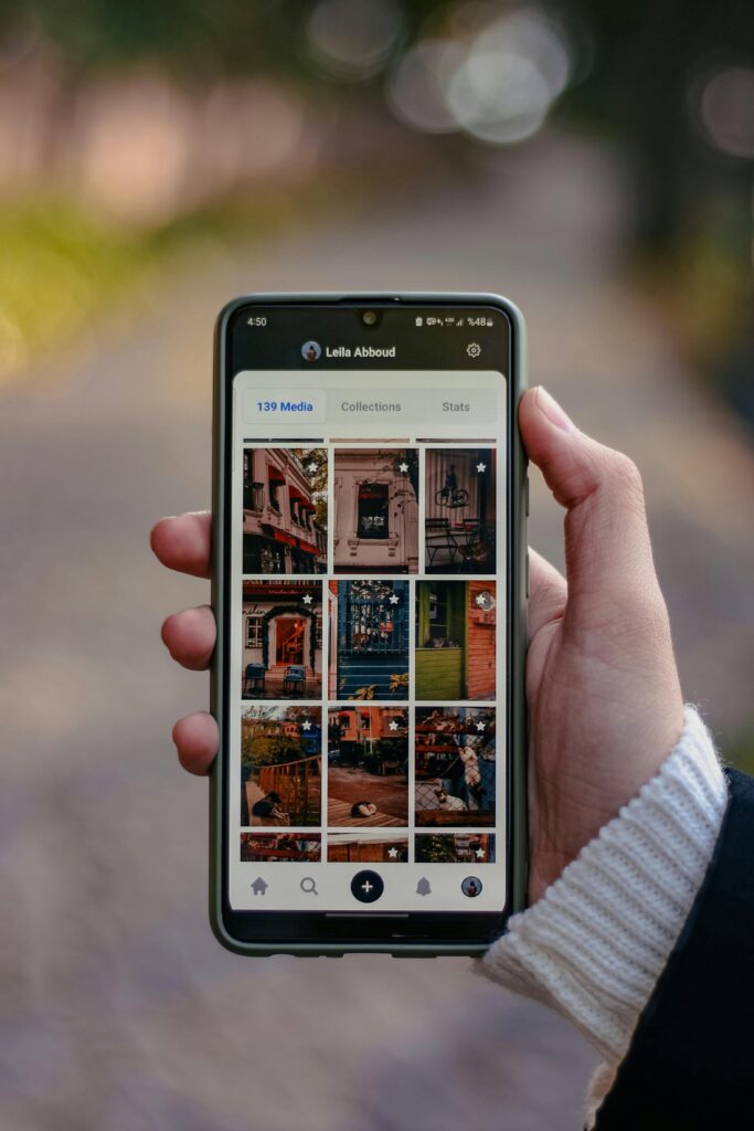 Person holding smartphone displaying an online photo gallery app outdoors.